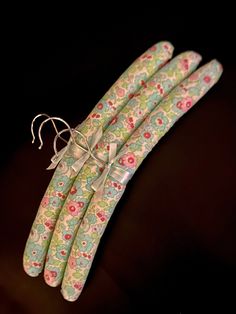 four green and pink flowered paper straws tied to each other on a black surface