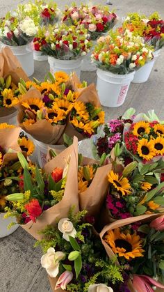 many different types of flowers in white buckets