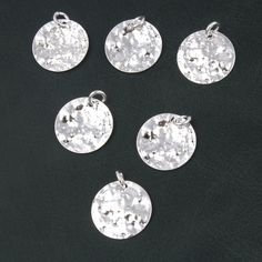 six silver pendants on a black background