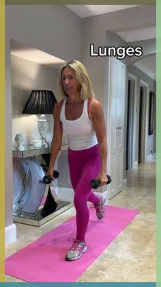 a woman is doing exercises with dumbbells on a pink mat in the living room