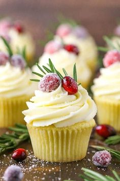 cupcakes with white frosting, cranberries and rosemary sprigs