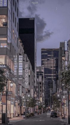 an empty city street at night with tall buildings on both sides and the sky in the background