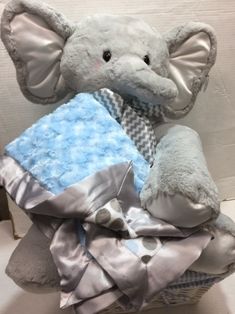 a stuffed elephant sitting on top of a pile of blankets