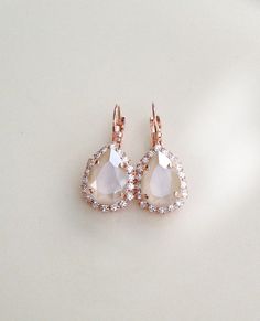 "Gorgeous pair of halo earrings featuring ivory cream crystals surrounded by a halo of sparkling clear crystals. The center stones in these are a luscious ivory color! Rose Gold plated settings, as shown. Also available in silver or gold plated. Please select desired metal finish from the drop down menu at check out. The earrings are 1 1/4\" long, 3/4\" wide Thanks for stopping by." Rose Gold Halo Earrings For Wedding, Elegant Teardrop Halo Setting Jewelry, Elegant Teardrop Halo Jewelry, Glamorous Pear-shaped Bridal Earrings As Gift, White Pear-shaped Jewelry With Halo Setting, White Sparkling Pear-shaped Jewelry, Wedding Bridal Earrings In Rose Gold With Halo Design, Rose Gold Halo Setting Earrings For Wedding, Rose Gold Halo Bridal Earrings For Wedding