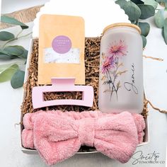 a pink bow tie in a gift box next to a water bottle and other items