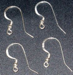 three pairs of silver earrings sitting on top of a black table next to each other