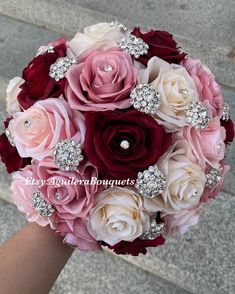 a bridal bouquet with pink, red and white flowers on the bride's arm