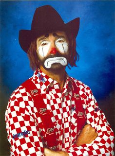 a man with his face painted like a clown wearing a red and white checkered shirt