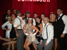 a group of people posing in front of a red curtain