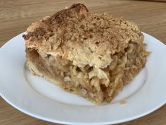 a piece of pie on a white plate sitting on top of a wooden table next to a fork