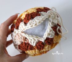 someone is holding a crocheted ball with scissors in it