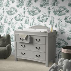 a baby crib in front of a wallpapered room with an elephant toy