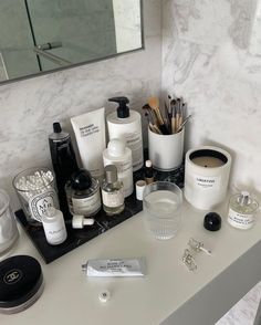 a bathroom vanity with various personal care items sitting on it's counter top and in front of a mirror