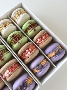 six macaroons are in a box with different designs on them, and one is purple