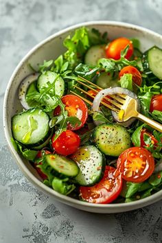 a white bowl filled with cucumbers, tomatoes and other vegtables