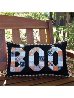 a wooden bench with a black and orange quilted pillow sitting on top of it