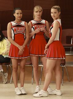 three girls in cheerleader outfits standing next to each other with their hands on their hips