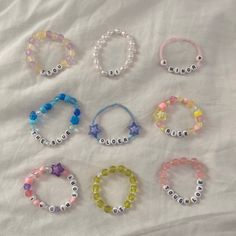 six bracelets with name beads on them sitting on a white cloth covered bed sheet