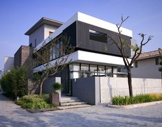 a modern house with black and white architecture on the outside, surrounded by greenery