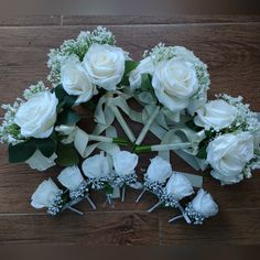 white roses and baby's breath are arranged in a circle on a wooden floor