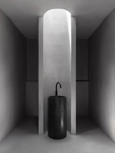 a black and white photo of a sink in a room with concrete walls on either side