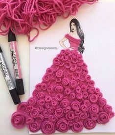 a crochet dress made out of pink yarn and rolled roses next to markers