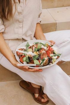 a woman is holding a plate of food