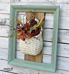 a white basket filled with flowers sitting on top of a wooden frame