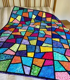 a multicolored quilt sitting on top of a bed