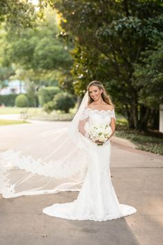 a woman in a wedding dress is posing for the camera with her veil blowing in the wind