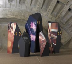 three black boxes sitting next to each other on top of a cement floor in front of a stone wall