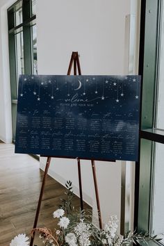 an easel with writing on it next to flowers