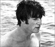 black and white photograph of a shirtless young man in the water looking at his cell phone