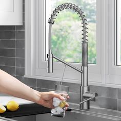 a woman is pouring water into a glass in front of a kitchen faucet