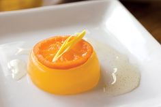 an orange on a white plate with a yellow stick sticking out of the top half