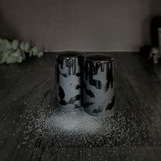 two black and white mugs sitting on top of a wooden table