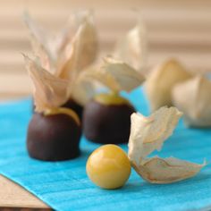 three chocolates with leaves and two olives on a blue napkin