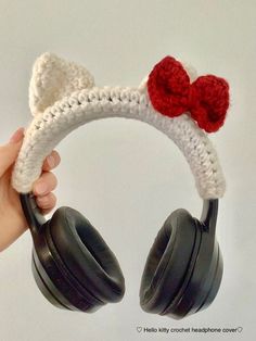 someone is holding up a crocheted headphone cover with a red bow on it