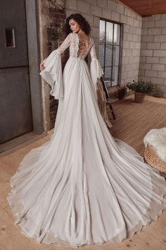 a woman in a wedding dress standing on a wooden floor next to a brick wall