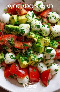 a white bowl filled with tomatoes, cucumber and mozzarella