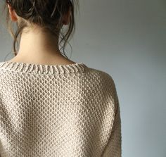 a woman with her back turned to the camera, wearing a white knitted sweater