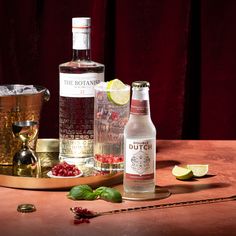 two bottles of booze next to some garnishes on a table with a gold tray