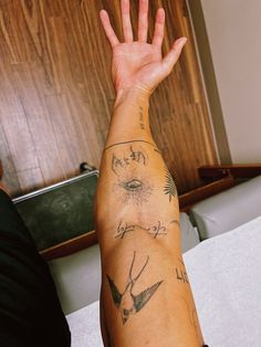 a man's arm with tattoos on it and his hand up in the air