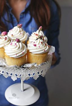 a woman holding a plate with cupcakes on it