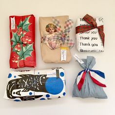 four wrapped gift bags with tags on them and some wrapping paper next to each other