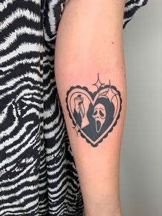 a woman's arm with a tattoo on it that has an image of two people in the shape of a heart