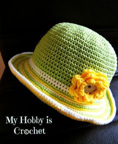 a crocheted green hat with yellow flower on the brim, sitting on a black chair