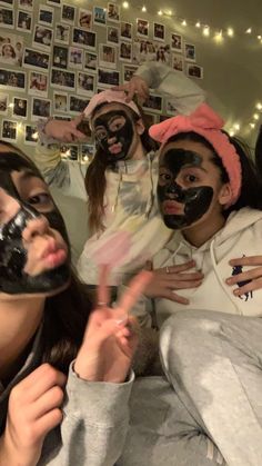 several people with their faces covered in black maskes posing for a photo while one woman holds her hand up to the camera