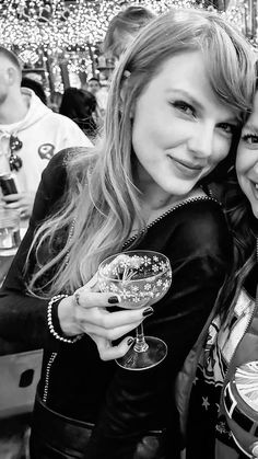 two women standing next to each other holding wine glasses