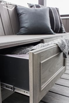 a wooden bench with two black pillows on top of it next to a gray pillow